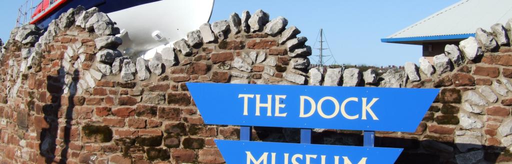 The Dock Museum sign in front of a lifeboat