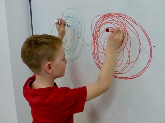 child drawing circles, using both hands