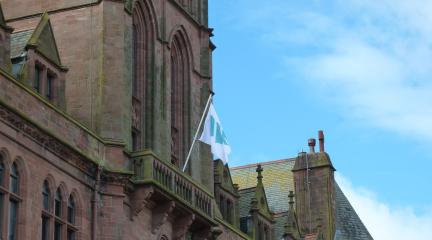 The Westmorland and Furness Council flag flying from a flagpole on a balcony at Barrow Town Hall