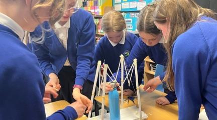 Primary school pupils working together around a model of a bridge
