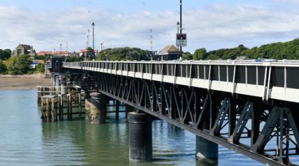 Looking along the railings in the outer edge of Jubilee Bridge over water, with Walney in the background