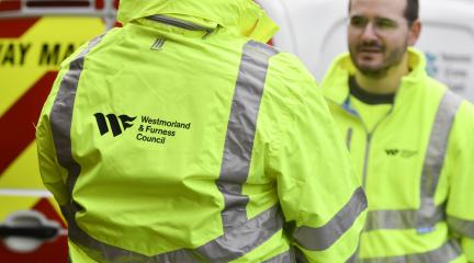 Two highways workers dressed in a Westmorland and Furness high-vis jackets discussing a job 