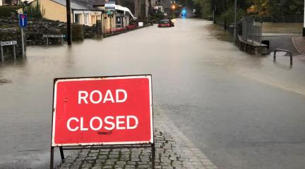 A sign saying 'road closed' in front of a road covered in water