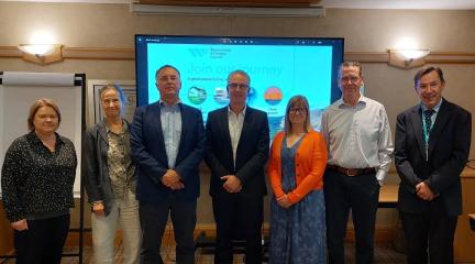 Seven people standing in front of a projector screen.