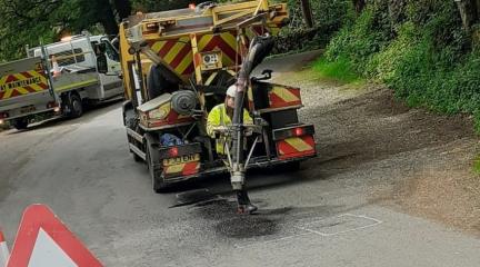 A man at work with a jet-patching machines fixing potholes on a road,