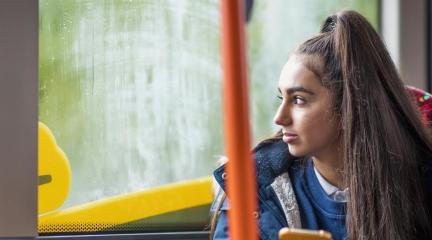 A school sitting on a bus looking out of the window.