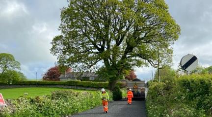 A newly surface dressed road in Westmorland and Furness with two highways operatives walking towards a vehicle 