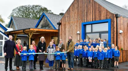 official opening ribbon cutting of new extension with guests and children