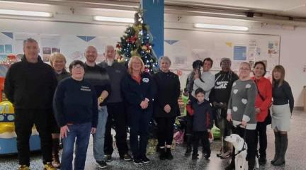 Men and women standing in front of a Christmas tree in Barrow Market.