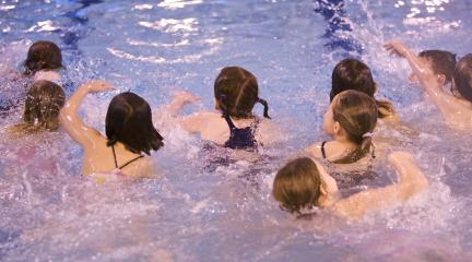 A group of children swimming in an indoor pool.