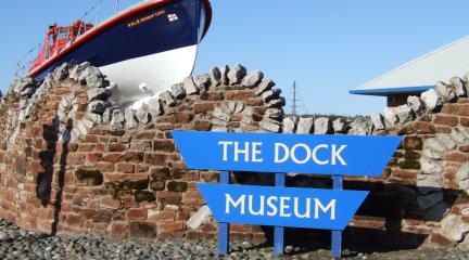 The Dock Museum sign in front of a lifeboat