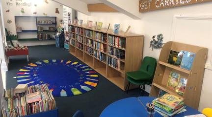 The children's library area in the new temporary library, with shelving for a wide range of books and tables and chairs for activities