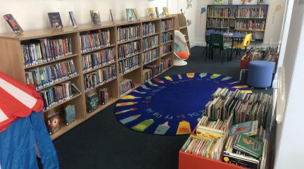 The children's library area in the new temporary library, with shelving for a wide range of books and tables and chairs for activities