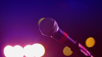 A microphone with stage lights in the background.