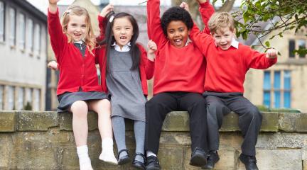 Children sitting on a wall in school uniform
