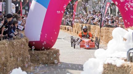 A kart going dowm the ramp at a soaabox derby.