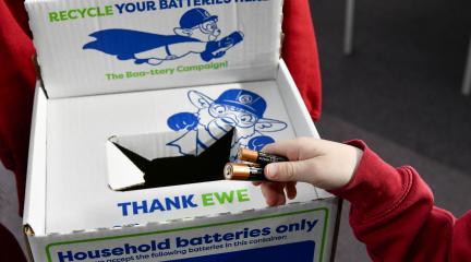 A child putting a used battery in a collection box at school