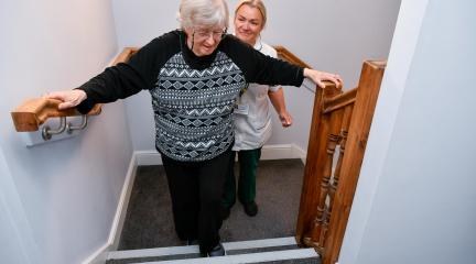 Older woman being helped up the stairs