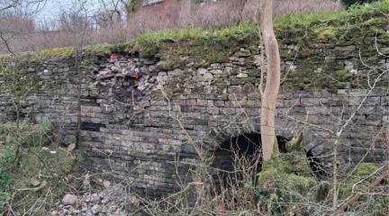 •	Picture shows the partial collapse of the retaining wall and culvert on the A684 at Smorthwaite. Currently two-way temporary traffic lights and safety barriers are in place to protect the damaged area and the wall is monitored regularly, but the repair is considered a high priority as further structural collapse could undermine the supported carriageway and lead to emergency road closures.