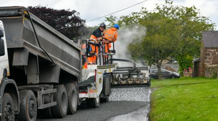 A highways crew undertaking surface dressing on a road.