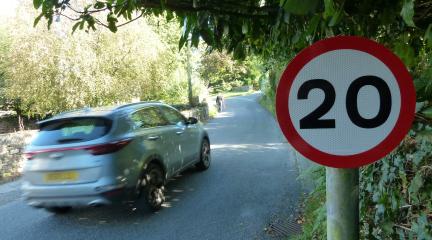 Sign showing 20mph speed limit with car passing by