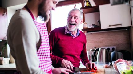 young man chopping food with older man in the kitchen