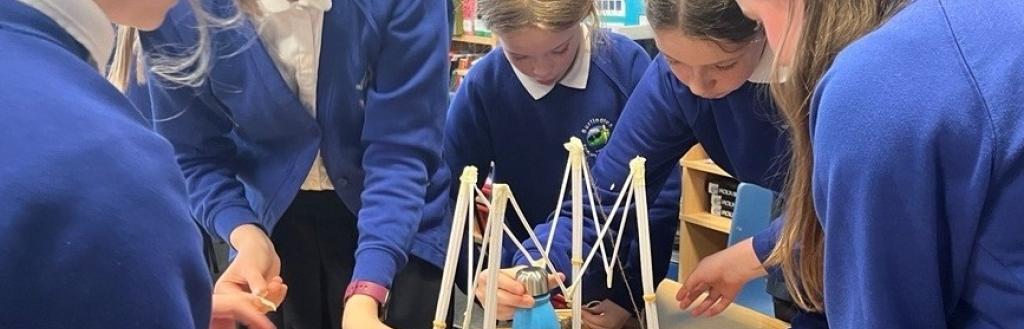 Primary school pupils working together around a model of a bridge