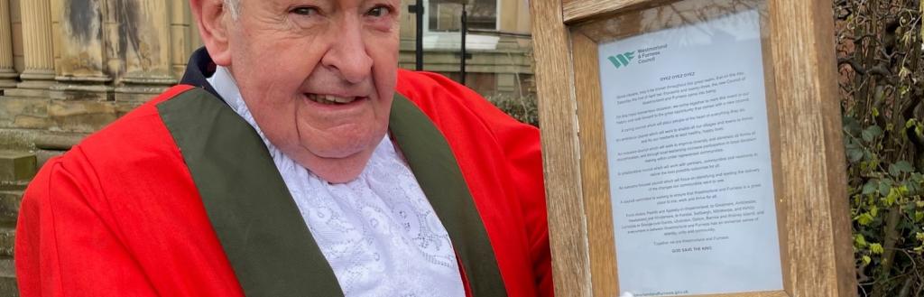 Town crier in traditional dress holding the proclamation in a wooden case