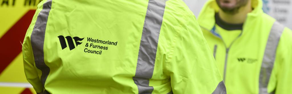 Two highways workers dressed in a Westmorland and Furness high-vis jackets discussing a job