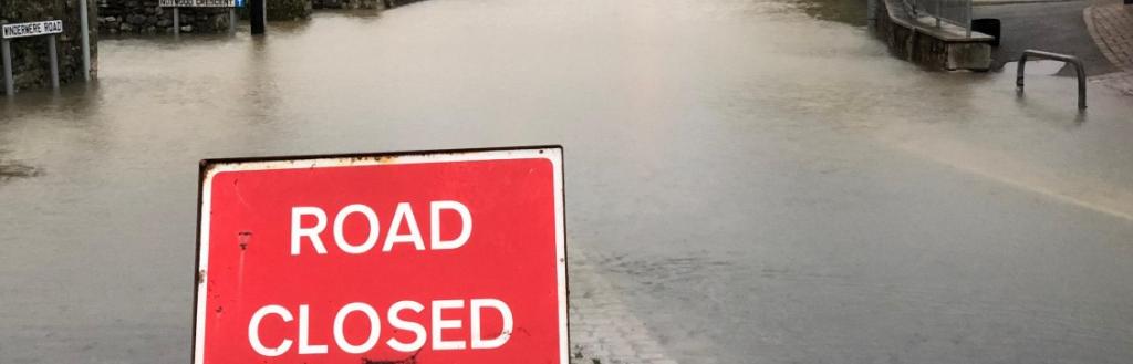 A sign saying 'road closed' in front of a road covered in water