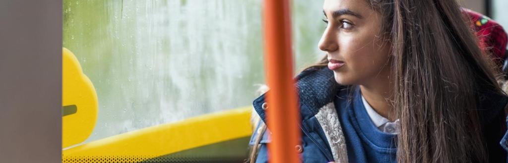 A female school student looking out of the window of a bus