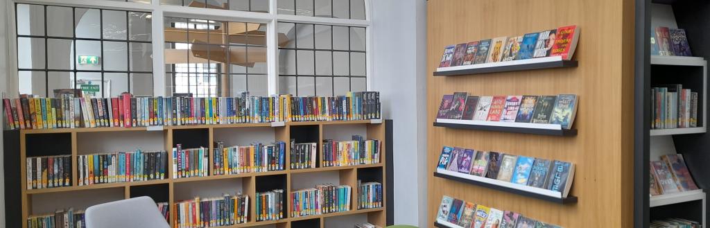 Seating area of Kendal Library with shelves of books and a big arched window