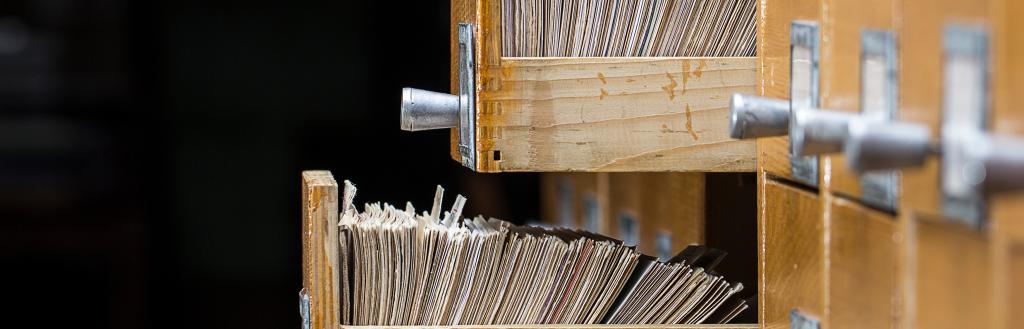 Archive records in open wooden drawers.