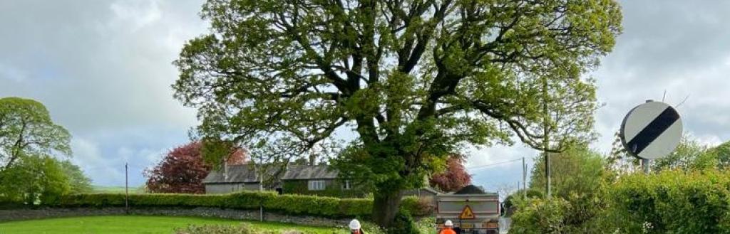 A newly surface dressed road in Westmorland and Furness with two highways operatives walking towards a vehicle 