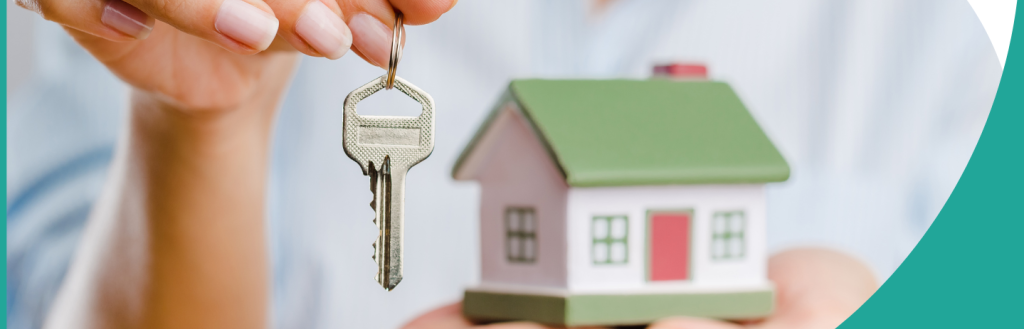 Person holding keys and a small building