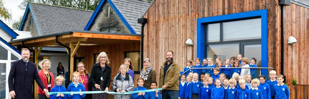 official opening ribbon cutting of new extension with guests and children