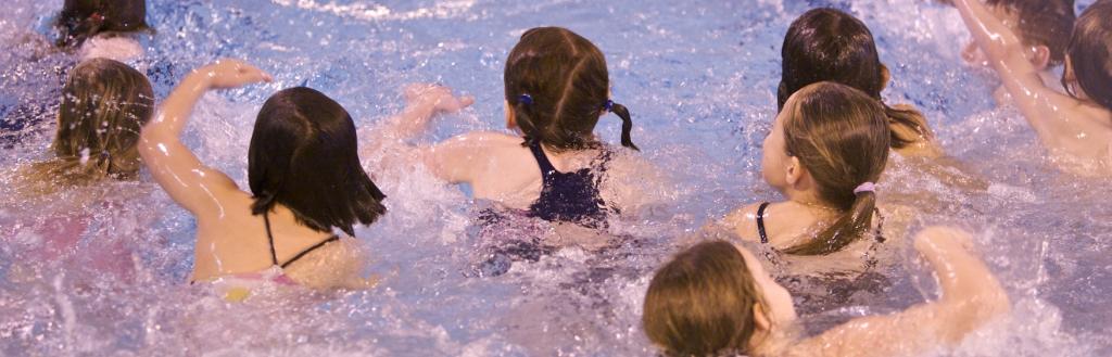 A group of children swimming in an indoor pool.