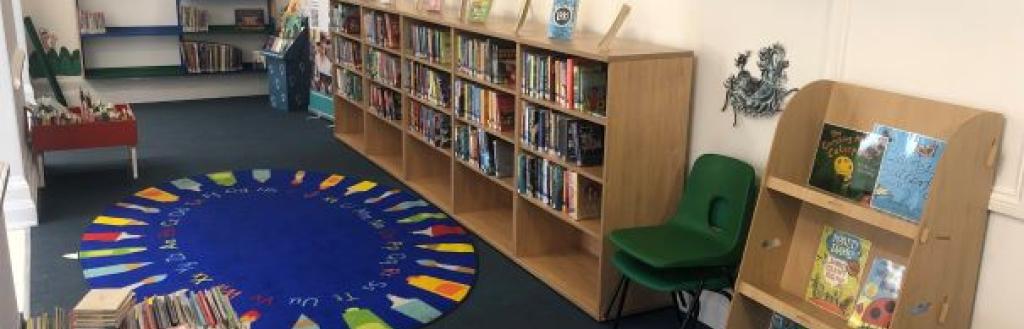 The children's library area in the new temporary library, with shelving for a wide range of books and tables and chairs for activities