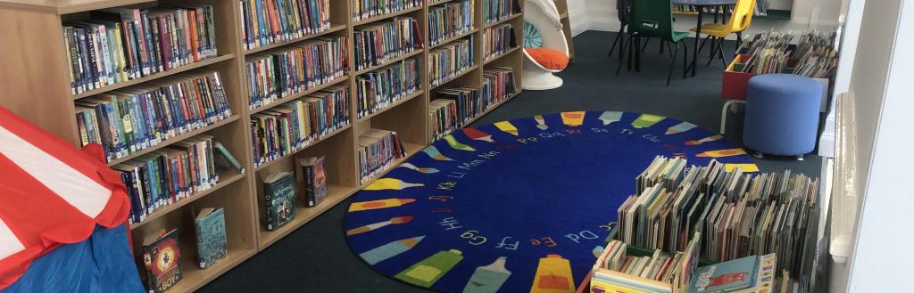 The children's library area in the new temporary library, with shelving for a wide range of books and tables and chairs for activities