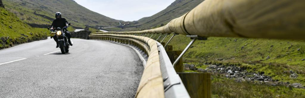 A motorcyclist rises along the newly resurfaced Kirkstone Pass road, alongside new wooden-clad crash barrier