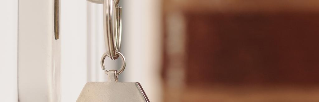 Key and keyring with house-shaped pendant in a white door