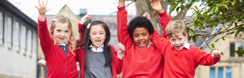 Children sitting on a wall in school uniform