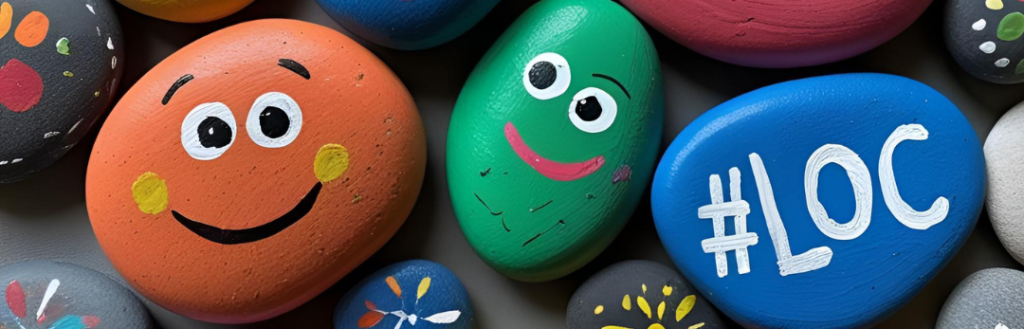 Pebbles painted with faces and hashtag #LOC for Love our Children week