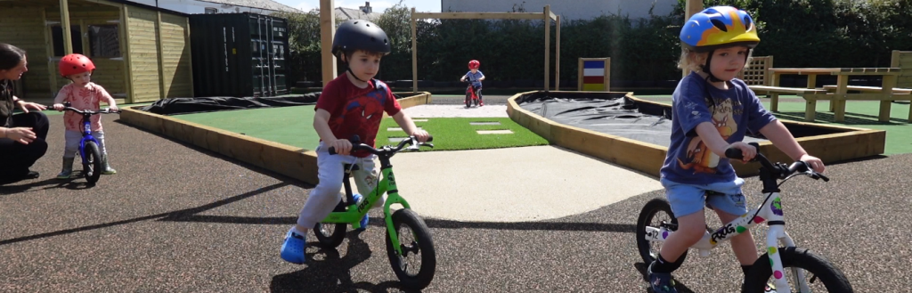 Children riding balance bikes on the new sensory trail