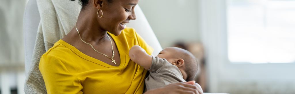 A mother breastfeeding her infant in a chair