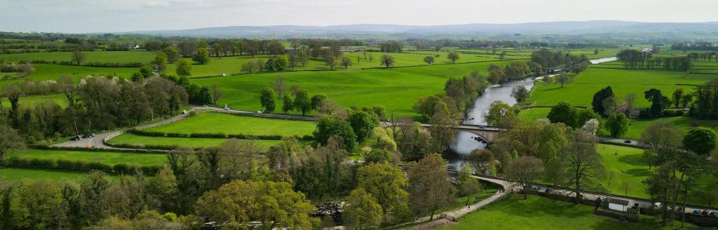 A green landscape with rolling fields with a river running through