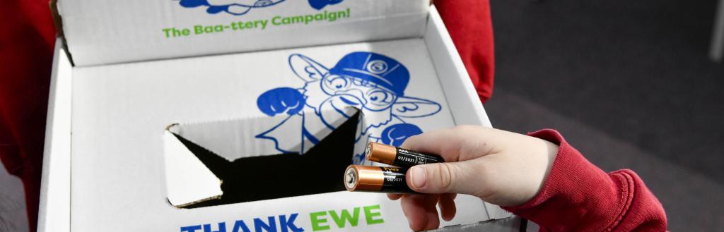 A child putting a used battery in a collection box at school