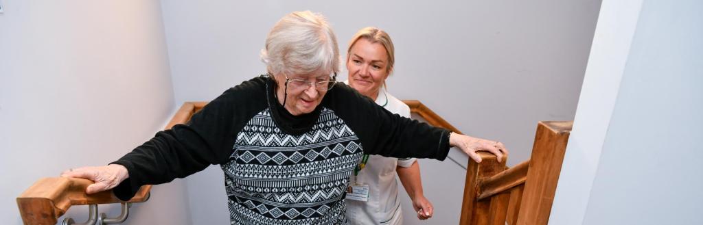 Older woman being helped up the stairs