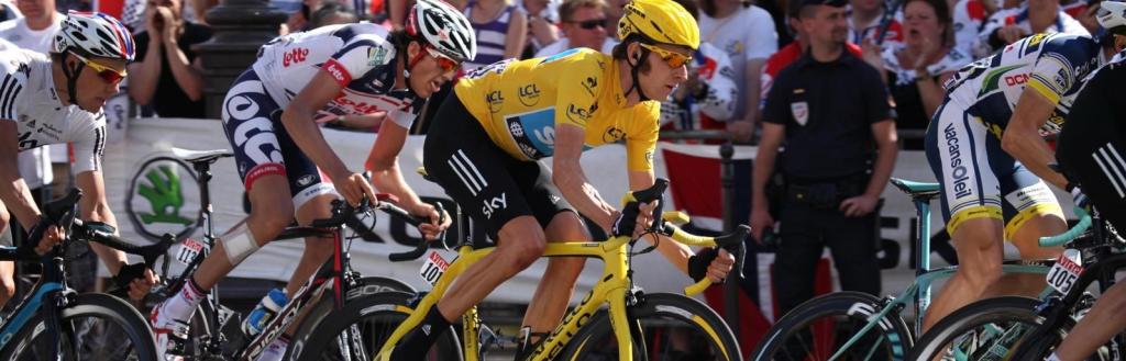 Bradley Wiggins riding a yellow bike and wearing a yellow top and cycling helmet, with spectators in the background
