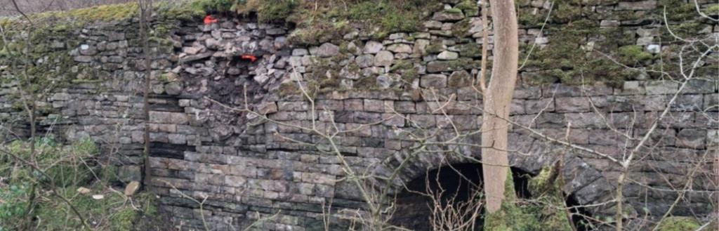 •	Picture shows the partial collapse of the retaining wall and culvert on the A684 at Smorthwaite. Currently two-way temporary traffic lights and safety barriers are in place to protect the damaged area and the wall is monitored regularly, but the repair is considered a high priority as further structural collapse could undermine the supported carriageway and lead to emergency road closures.